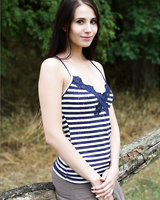 Long legged brunette undressing in a field to spread naked and rub her clit