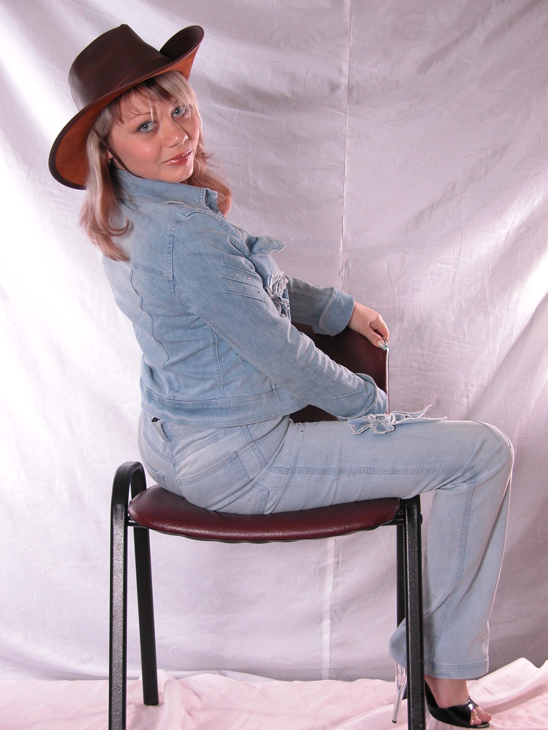 Girl in hat poses on the chair